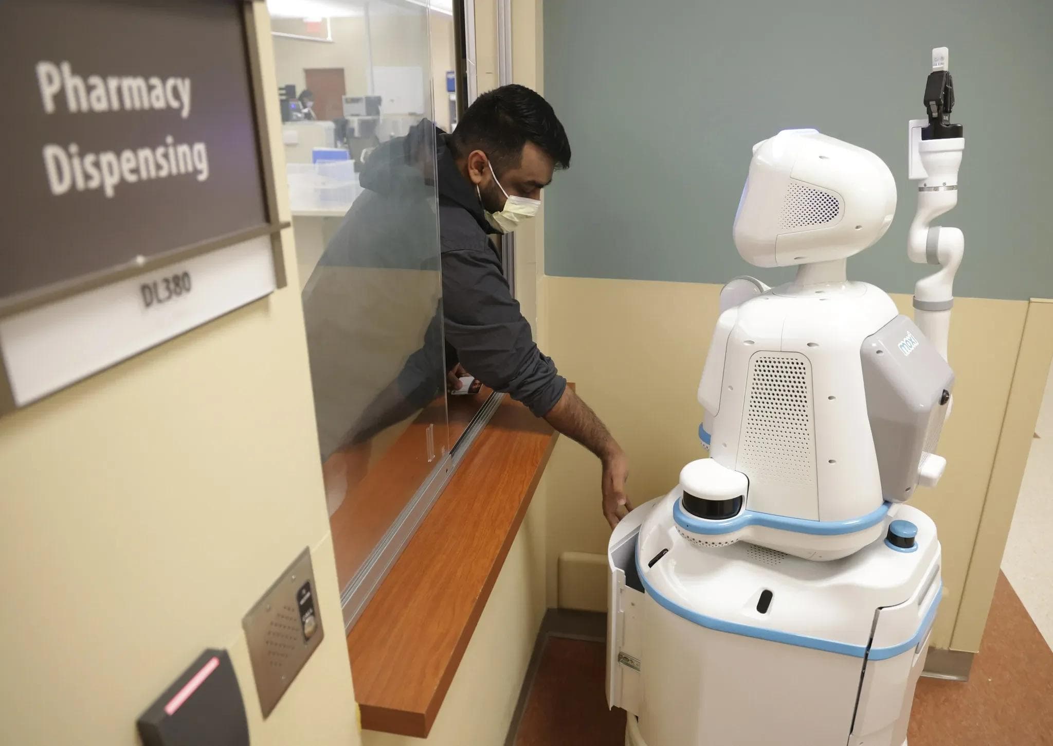 Moxi, a white hospital service robot with a screen face and a raised gripper arm.